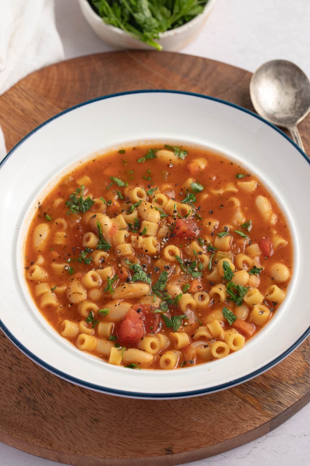 Bowl of Pasta Fagioli with beans and tomatoes on a wooden board