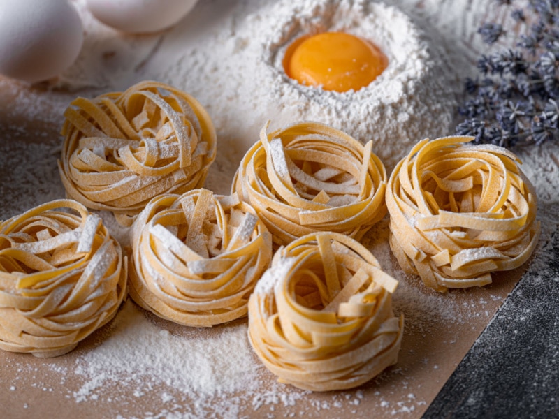 Raw Pasta Noodles with Flour and Egg on Table