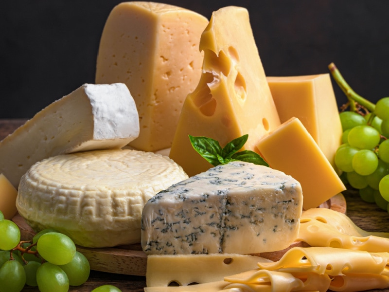 Variety of Cheeses with Grape on a Wooden Cutting Board