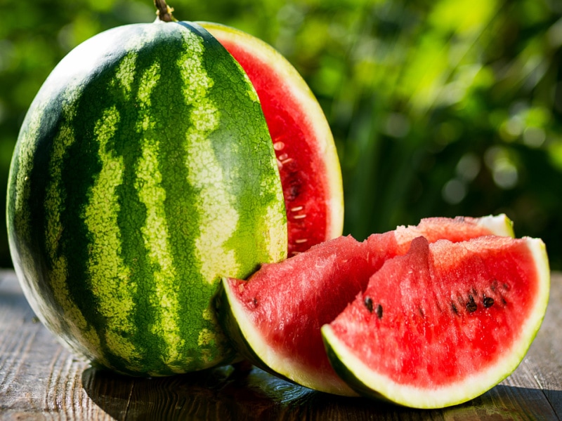 Cut Watermelon on a Wooden Table with Two Watermelon Slices on the Side