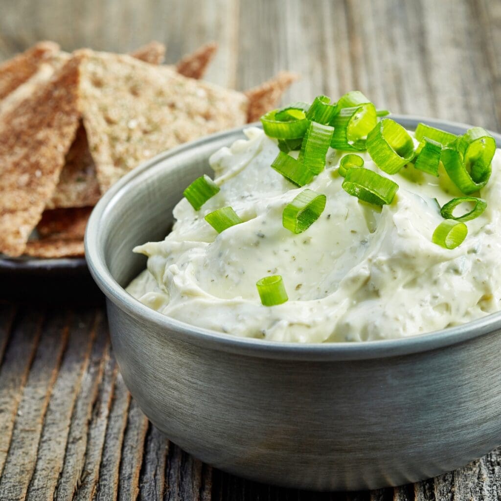 Bowl of blue cheese dip with onion leaves.