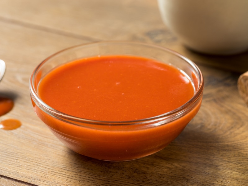 Spicy Hot Organic Red Buffalo Sauce in a Small Glass Bowl on a Wooden Table