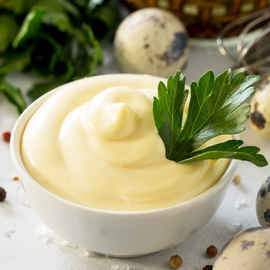 5 Best Kewpie Mayo Substitutes featuring Kewpie Mayo in a White Bowl and Garnish of Parsley