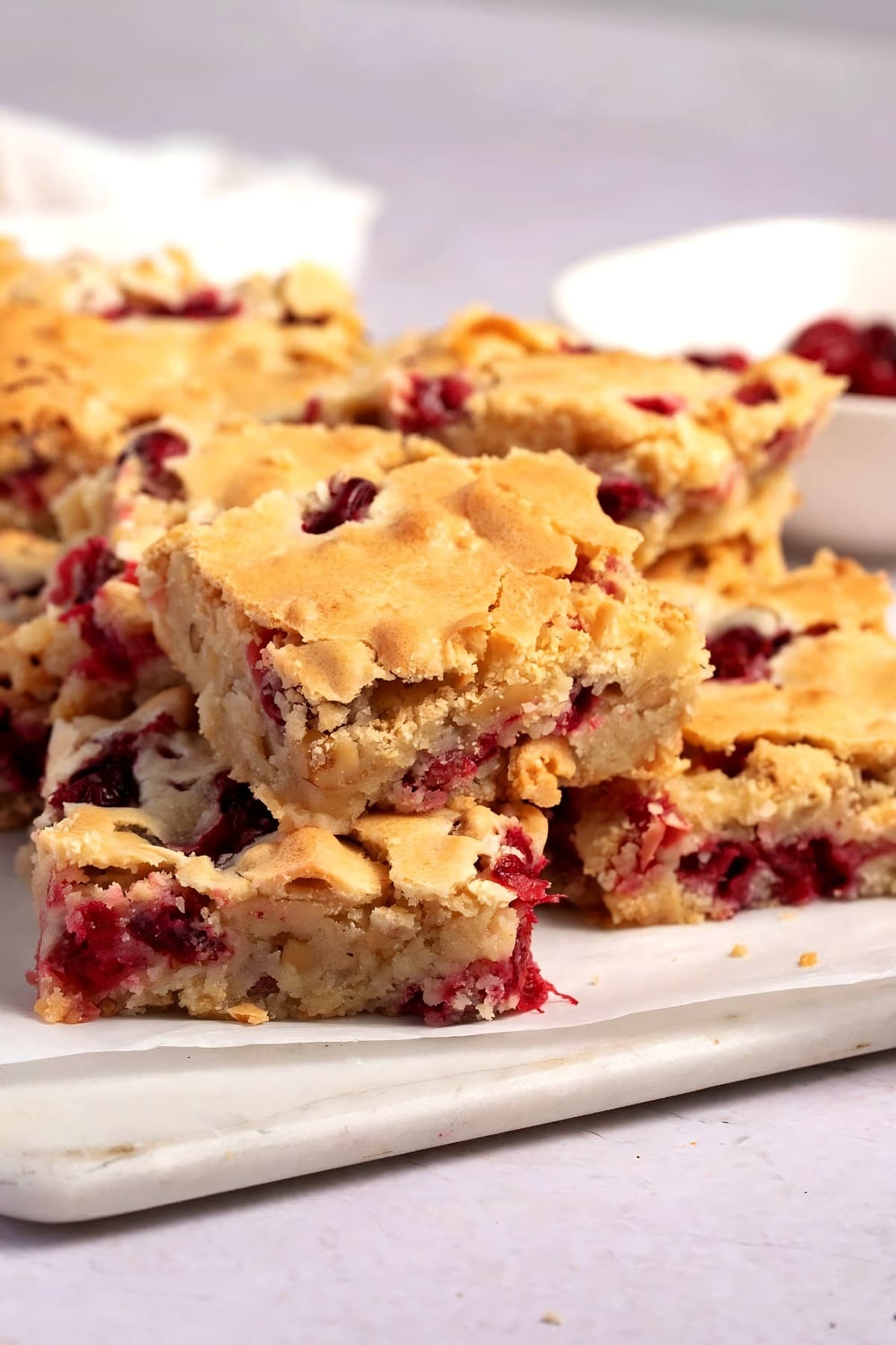Stack of cranberry cake bars on a wooden board. 