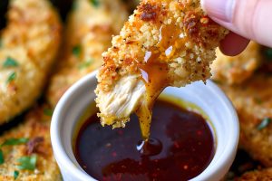 Dipping Crispy Baked Chicken Tender in Barbecue Sauce