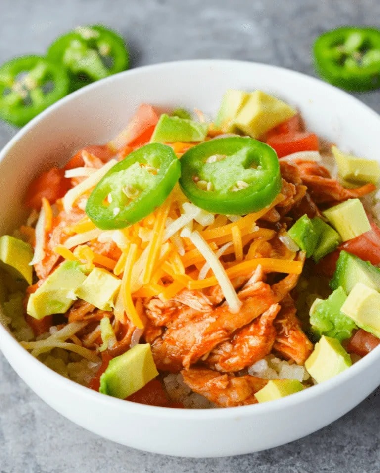 Keto Chicken Enchilada with avocado, cheese and cheese served in a white bowl. 