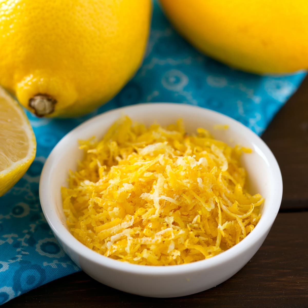 Bowl of Lemon Zest and Fresh Lemons on a Wooden Table