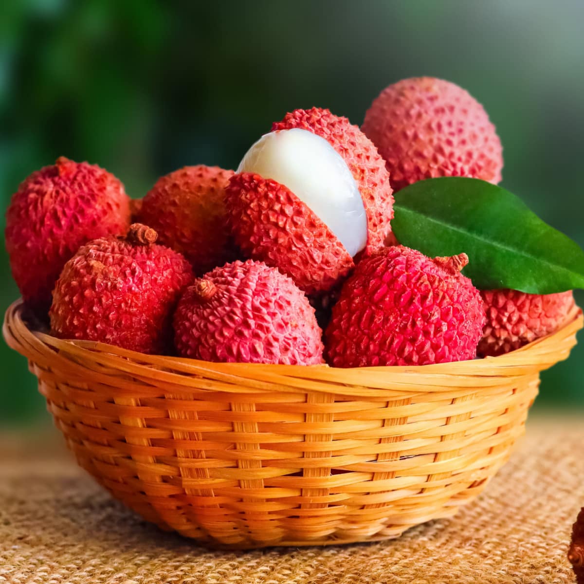 Bunch of Ripe Lychees in a Rattan Basket, One is Peeled