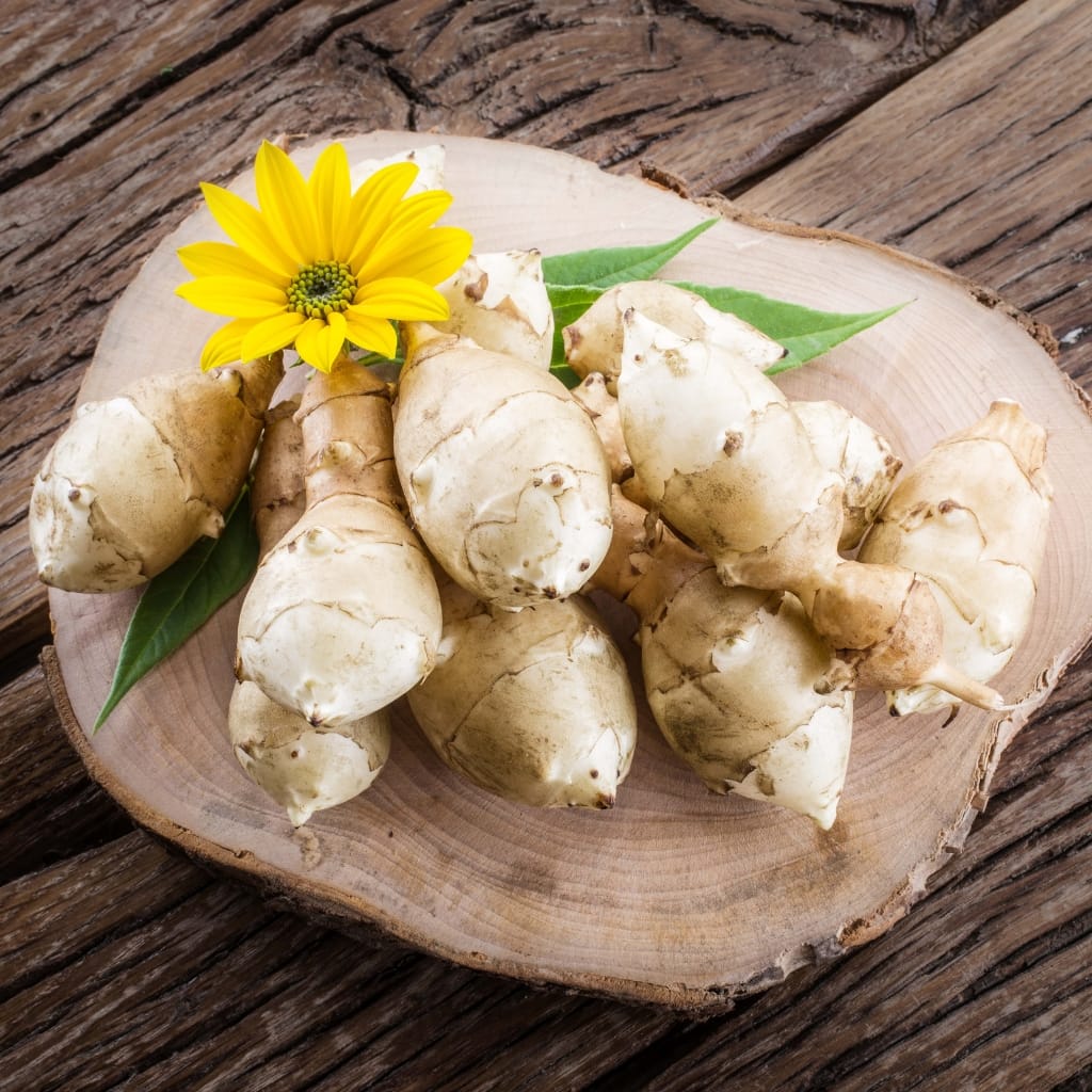 Pile of Sunchokes on a Wooden Board with a Yellow Flower