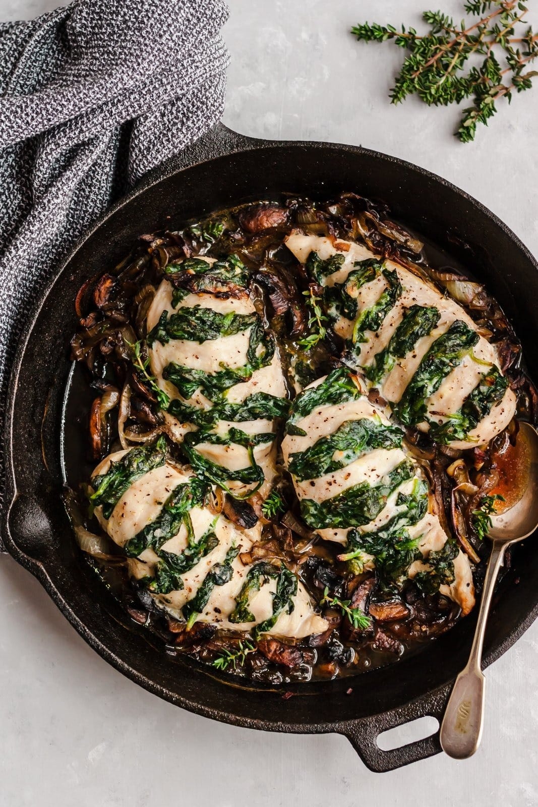 Goat cheese & spinach stuffed chicken breast with caramelized onions and mushrooms on skillet. 