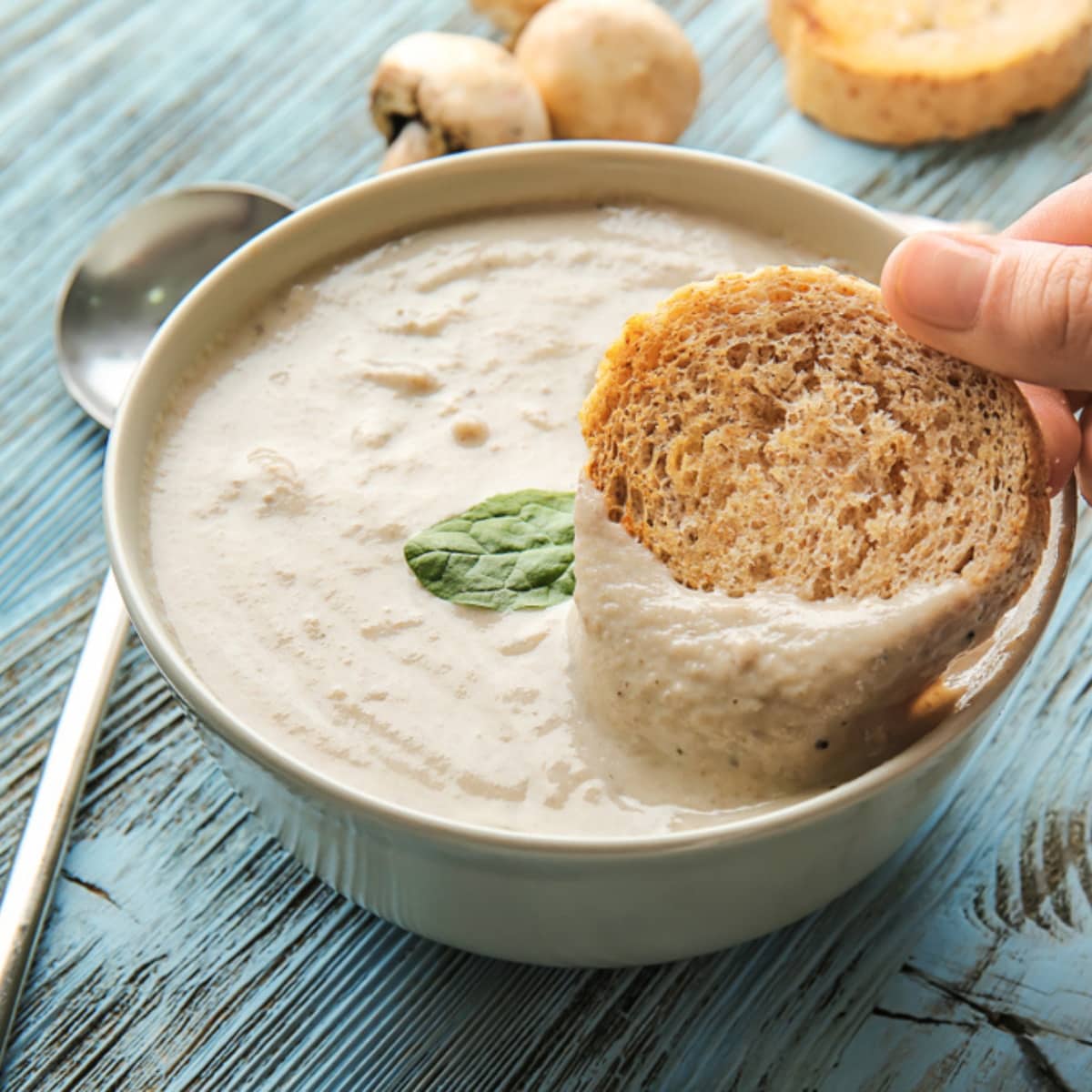 Slice of Bread Dipped into a Bowl of Thick Mushroom Soup