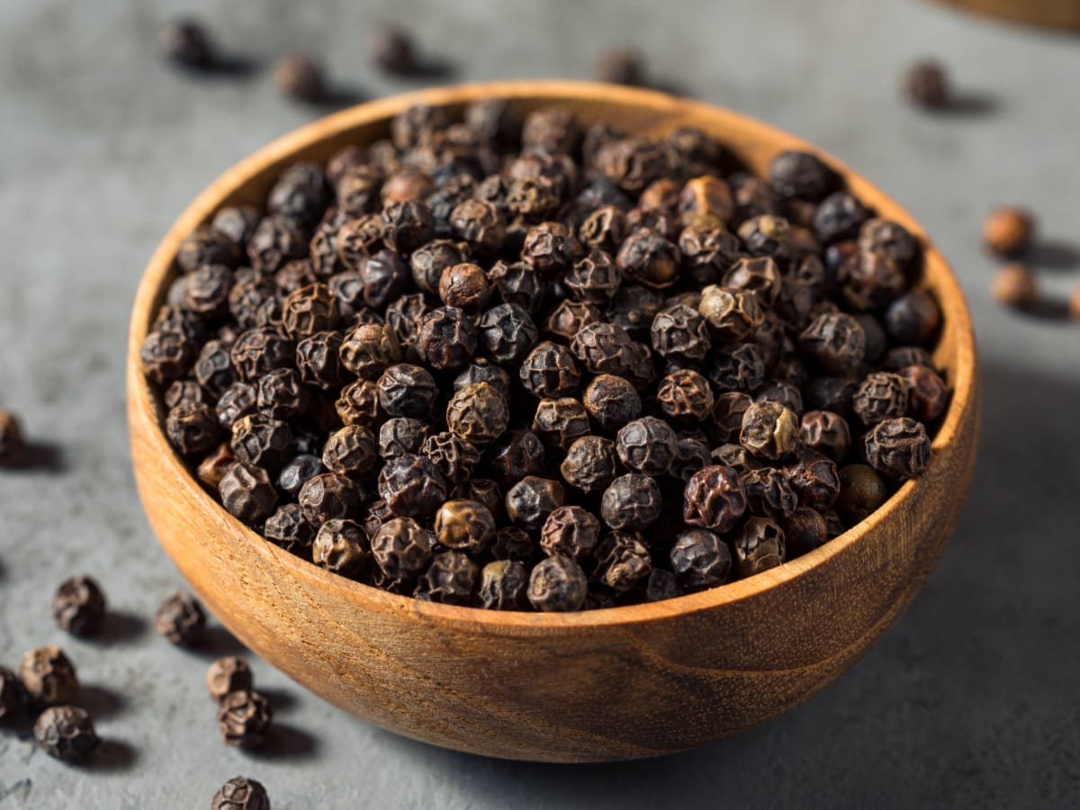 Raw Organic Black Peppercorns in a Wooden Bowl