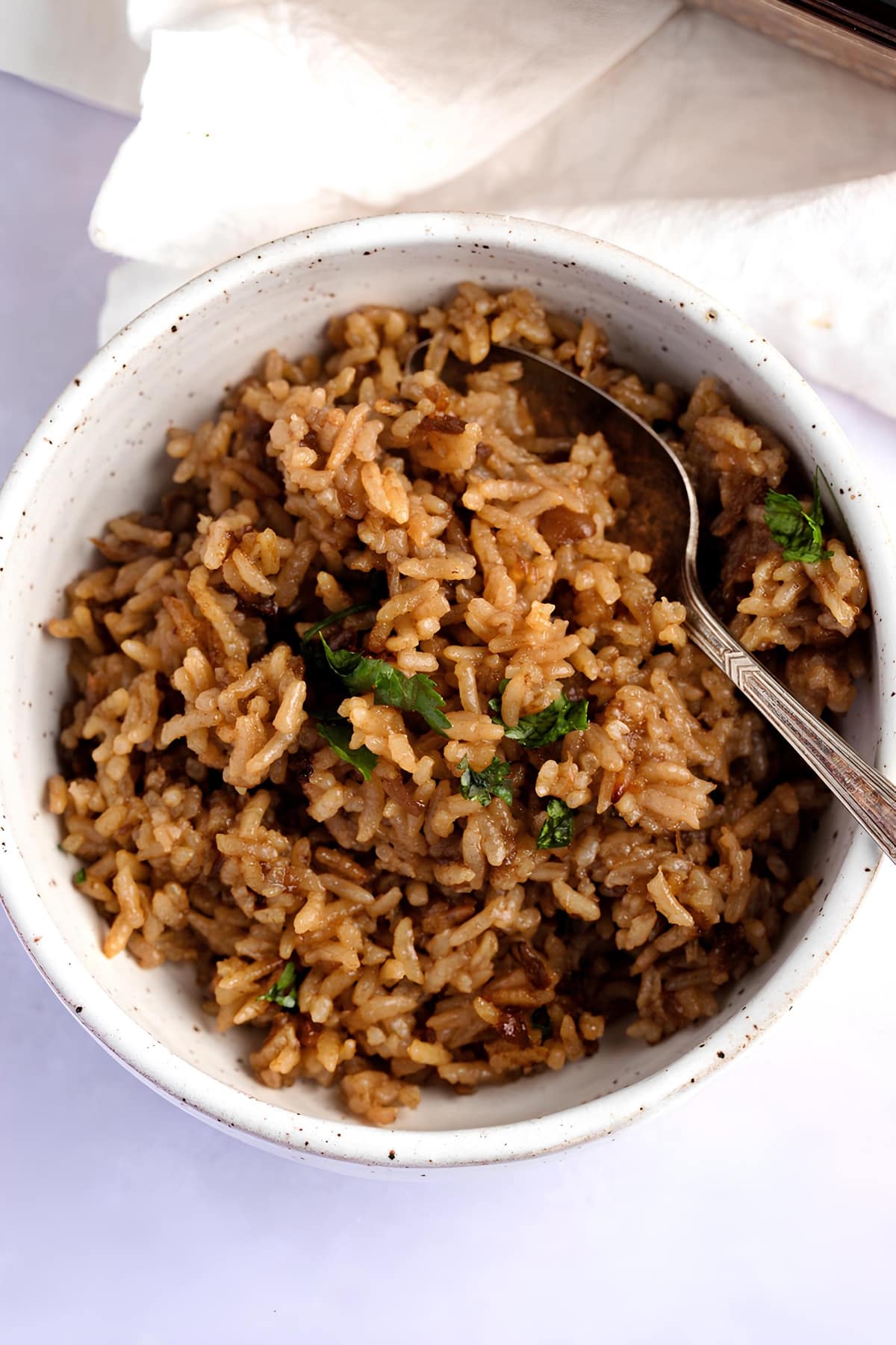 Stick of Butter Rice served in a white bowl, with spoon  garnished with parsley leaves