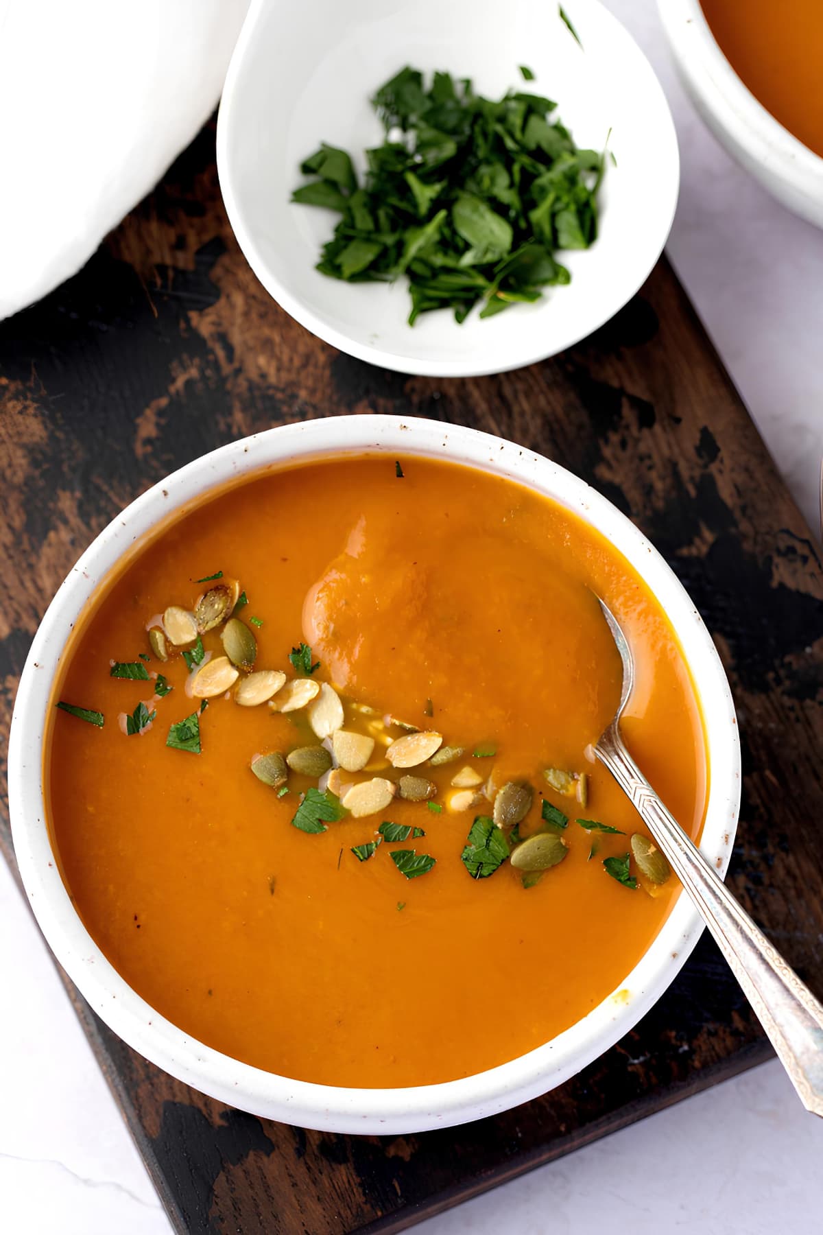 Bowl of comforting homemade pumpkin soup with cream and squash seeds. 
