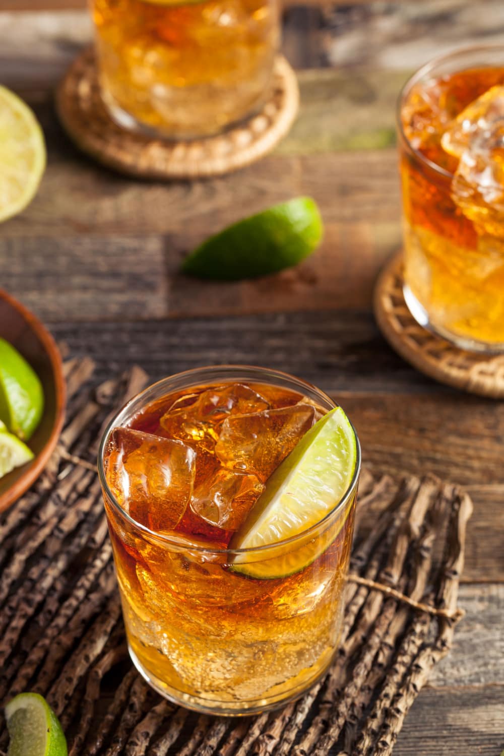 Top view of a glass of Dark and Stormy Cocktail filled with ice, garnished with a slice of green lime on top