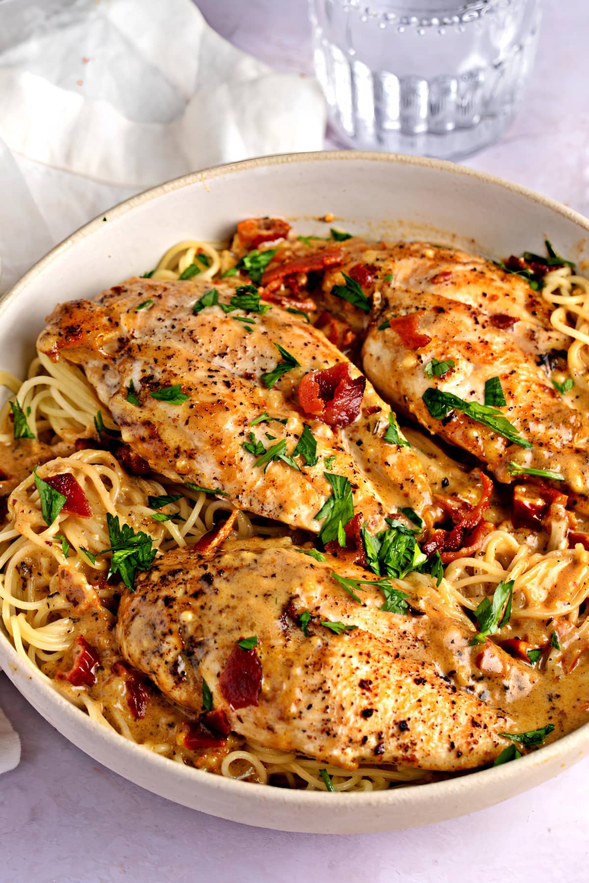 Creamy chicken breasts with pasta, bacon and chopped herbs. 