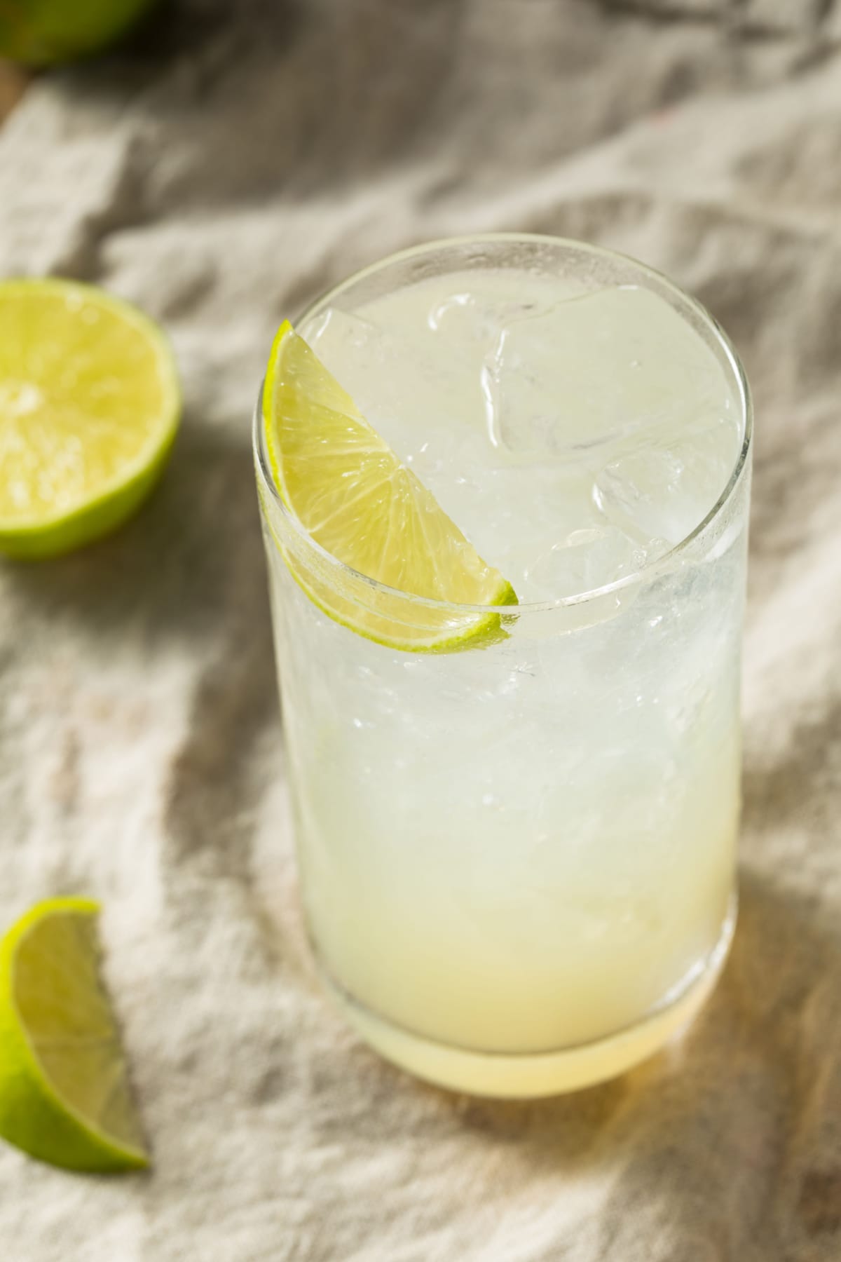 Ice cold glass of Gin Rickey on a highball glass, garnished with a lime wedge