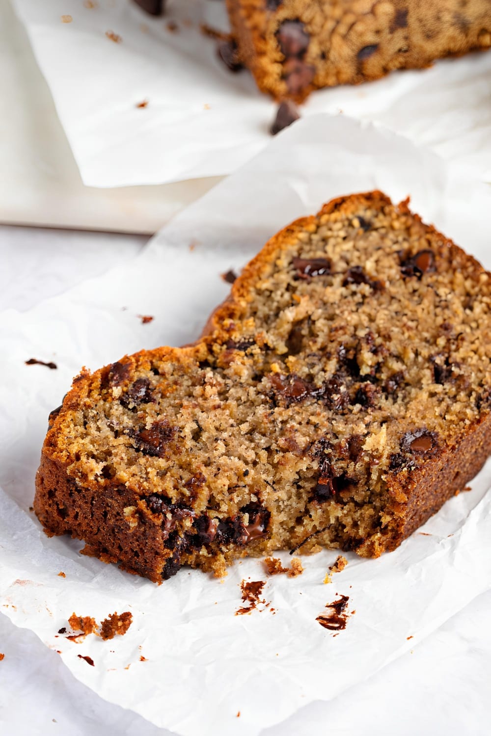 A loaf of chocolate chip banana bread sitting on top of parchment paper