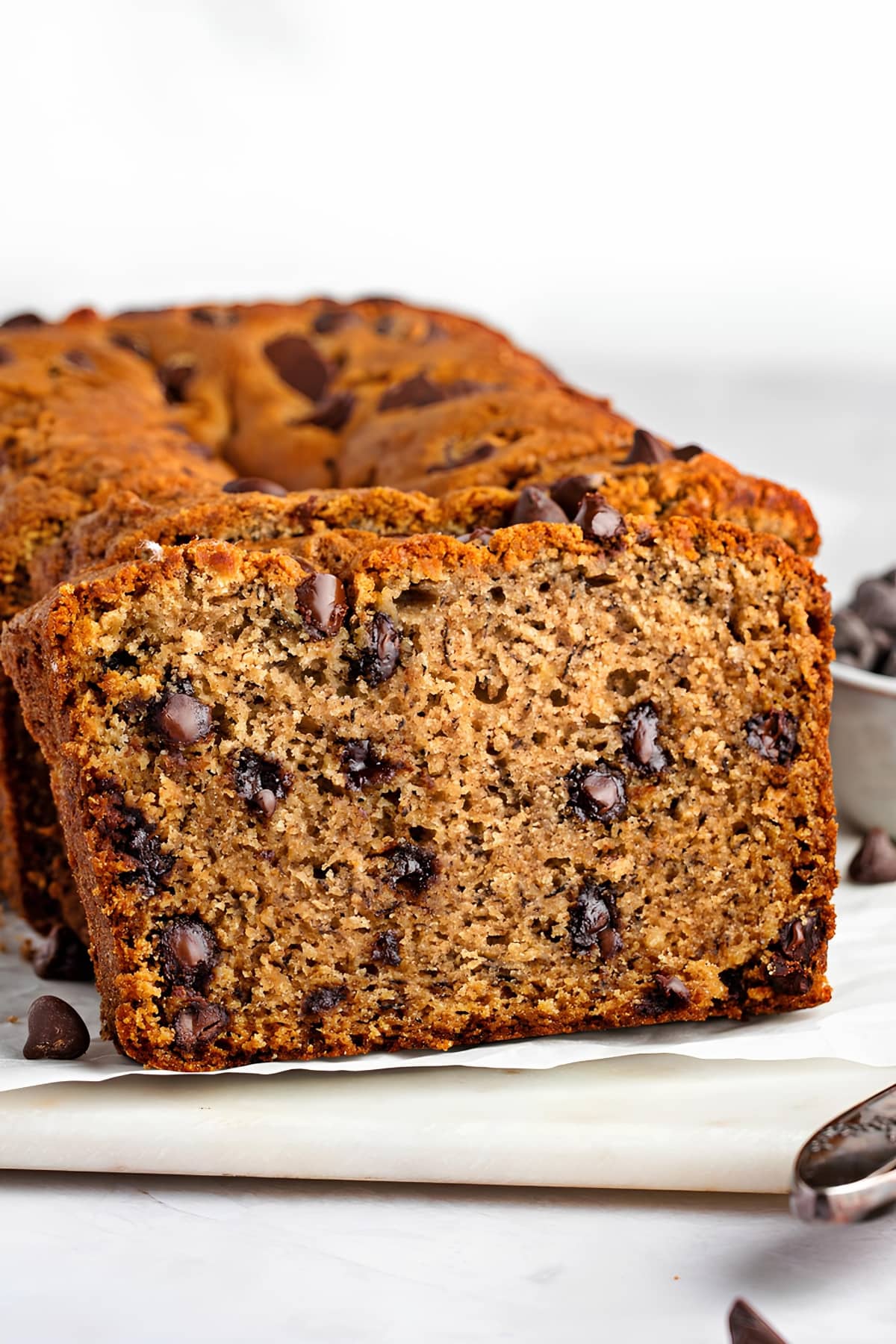 A loaf of chocolate chip banana bread on a cutting board.