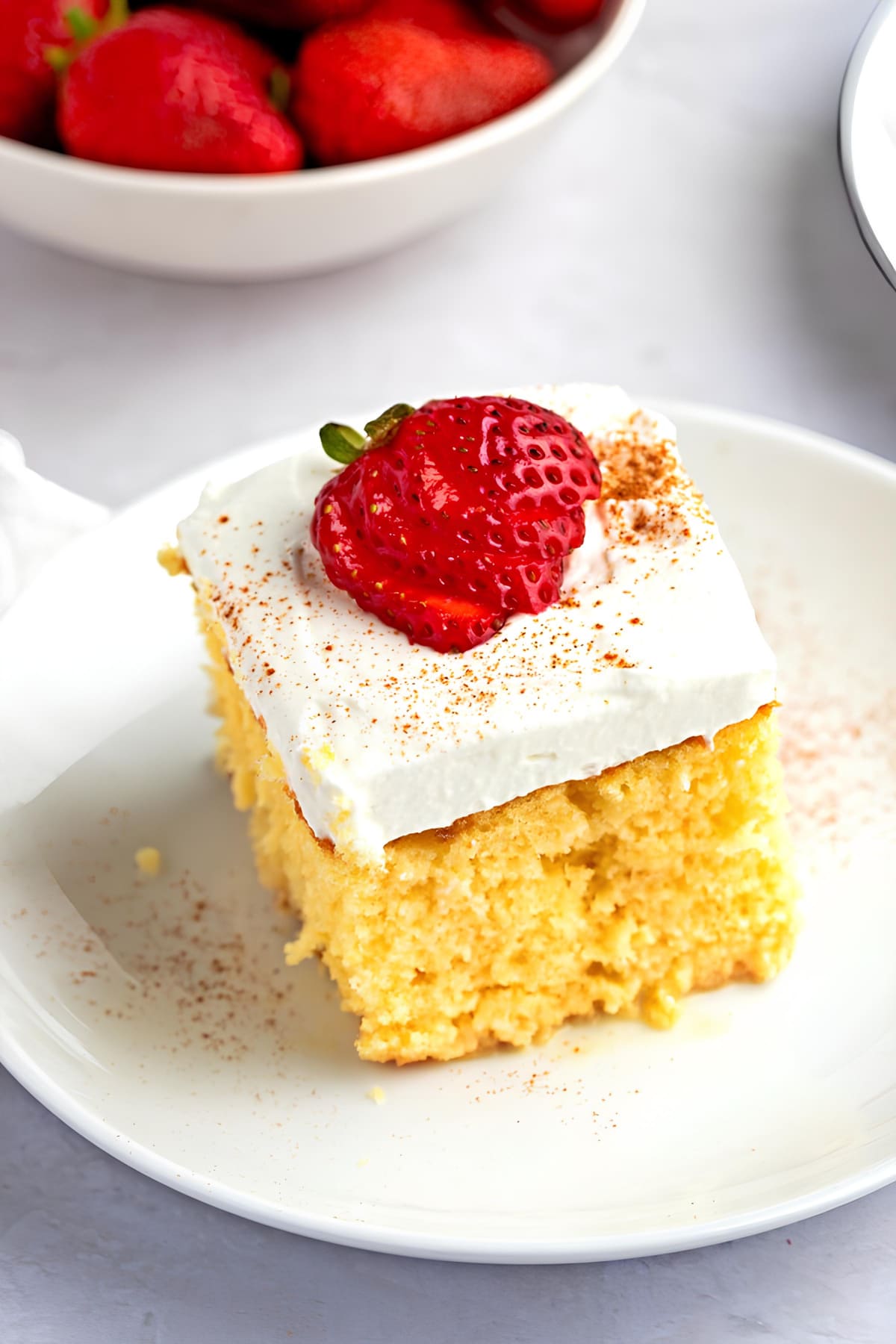 Slice of Tres Leches Cake with fresh strawberry on top. 