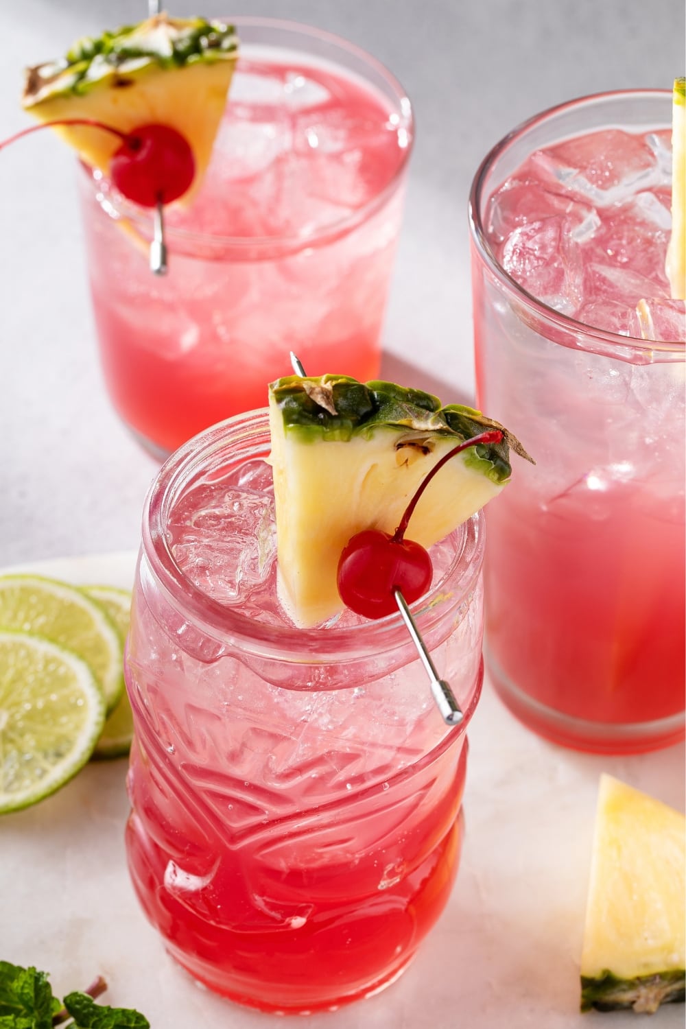 3 Glasses of Boozy and Refreshing Singapore Sling Garnished With Fresh Pineapple Slice and Cherries 