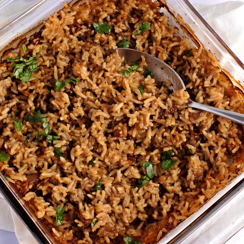 Stick of butter, brown colored cooked rice served on a glass baking dish