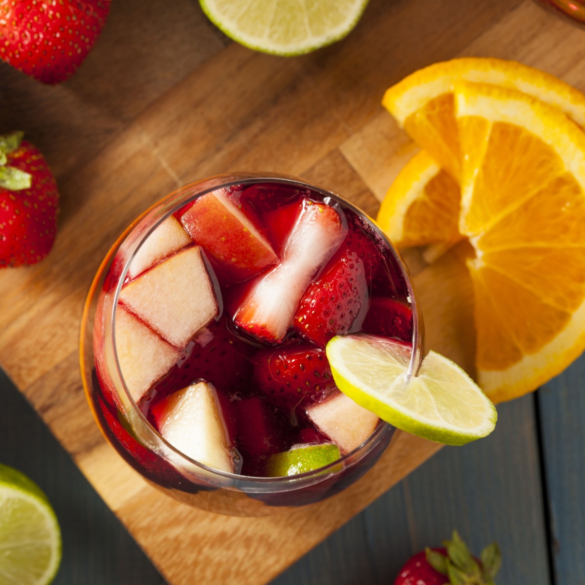 Top view of a glass of Red Sangria with strawberries, apples, and oranges garnished with lime wheel 