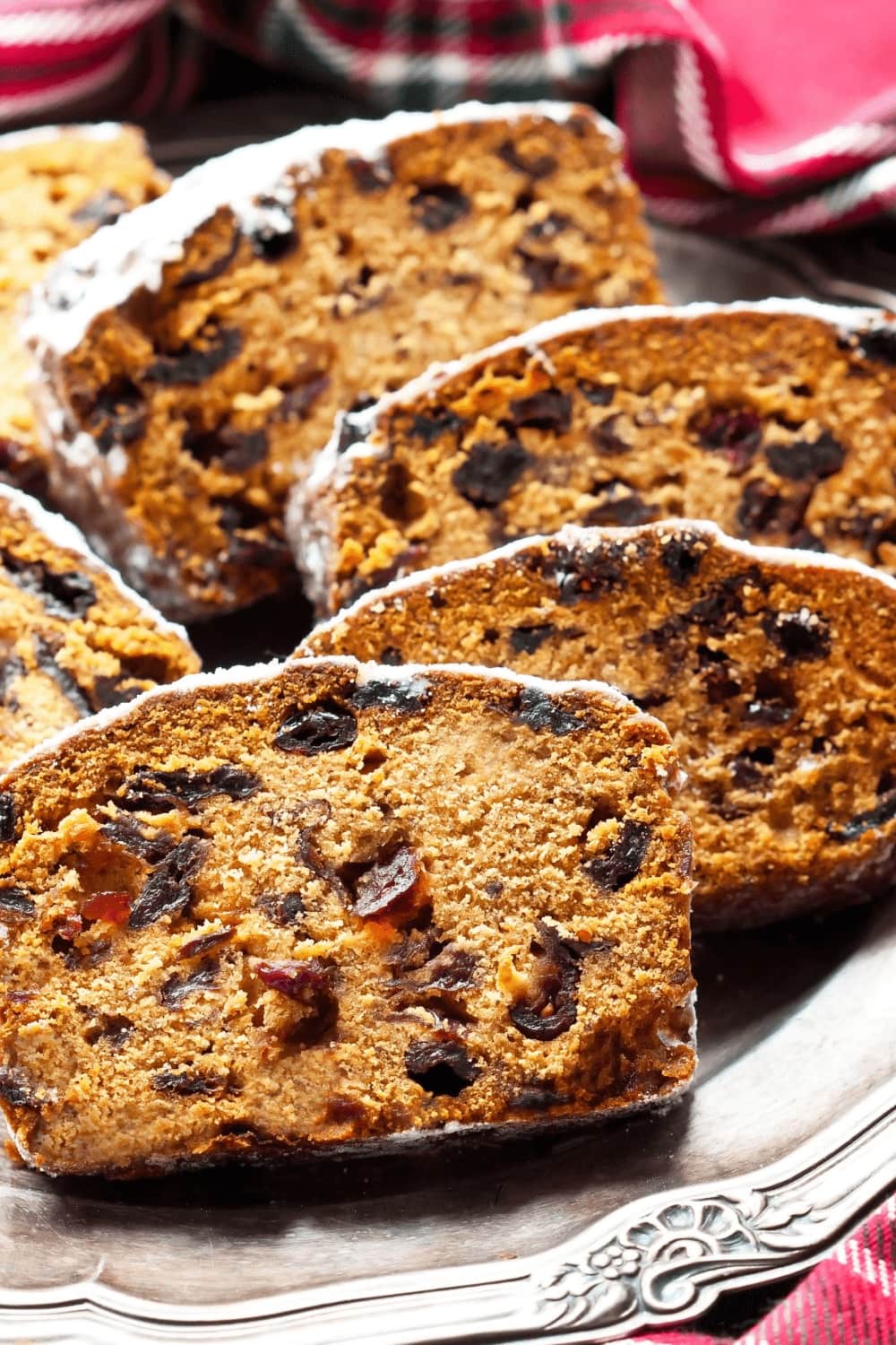 Sliced applesauce loaf cake with raisin and walnuts topped with a dusting of powdered sugar.