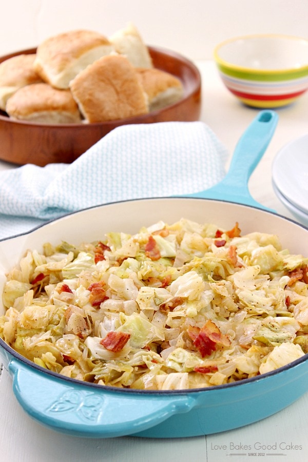 Cabbage with fried bacon cooked in a blue ceramic pan. 