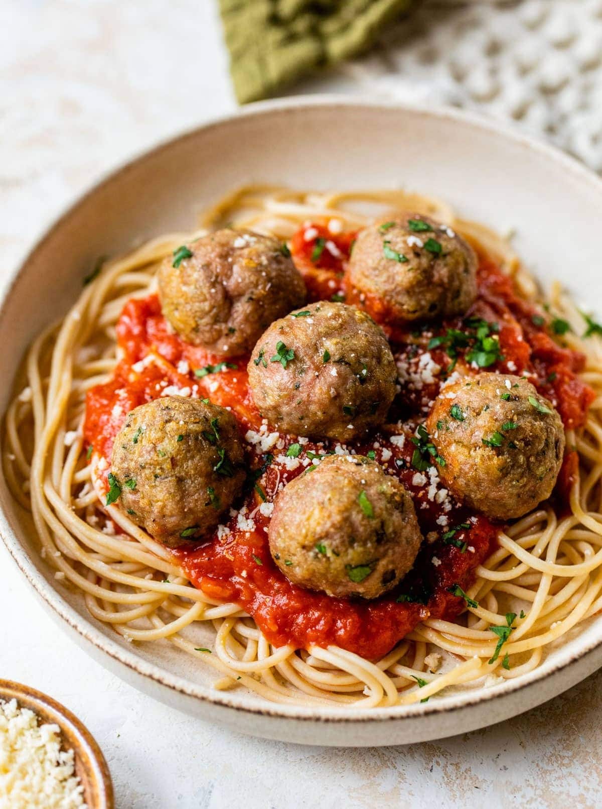 Pasta topped with turkey meatballs and tomato sauce garnished with grated parmesan cheese and chopped parsley. 