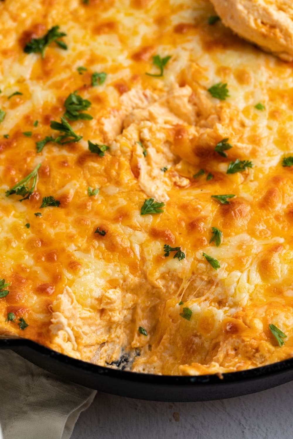 Cheesy dip with chicken meat cooked on a skillet.