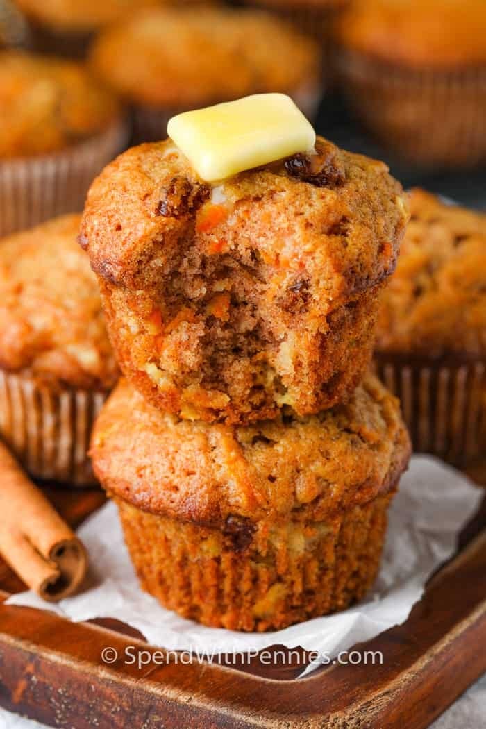 Bunch of homemade Carrot Muffins on a wooden board garnished with butter and fresh cinnamon stick on the side