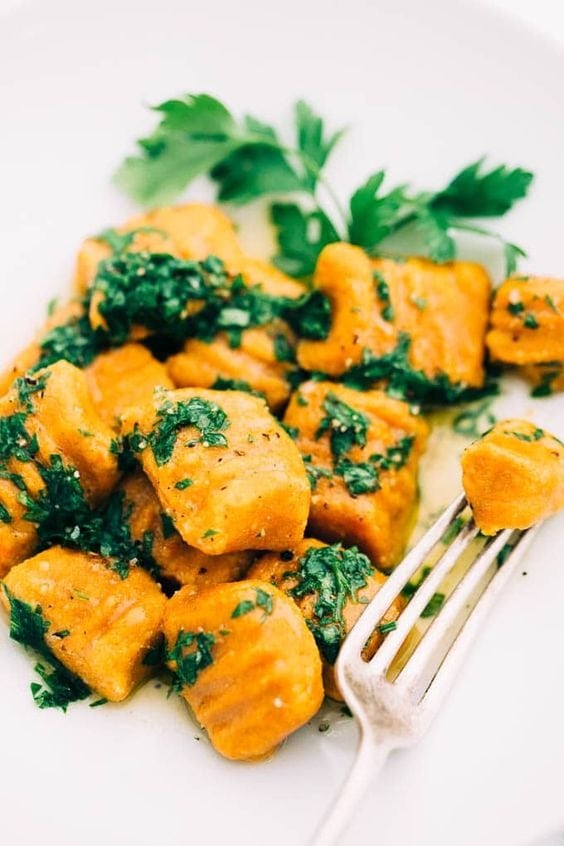 Carrot gnocchi with celery leaves served on a plate. 