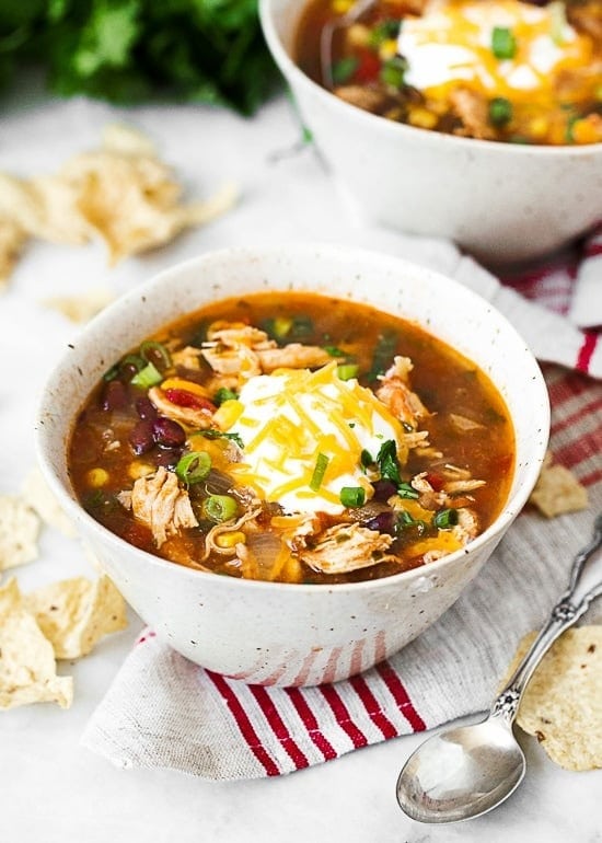 Bowl of chicken enchilada soup topped with sour cream nd grated cheese. 