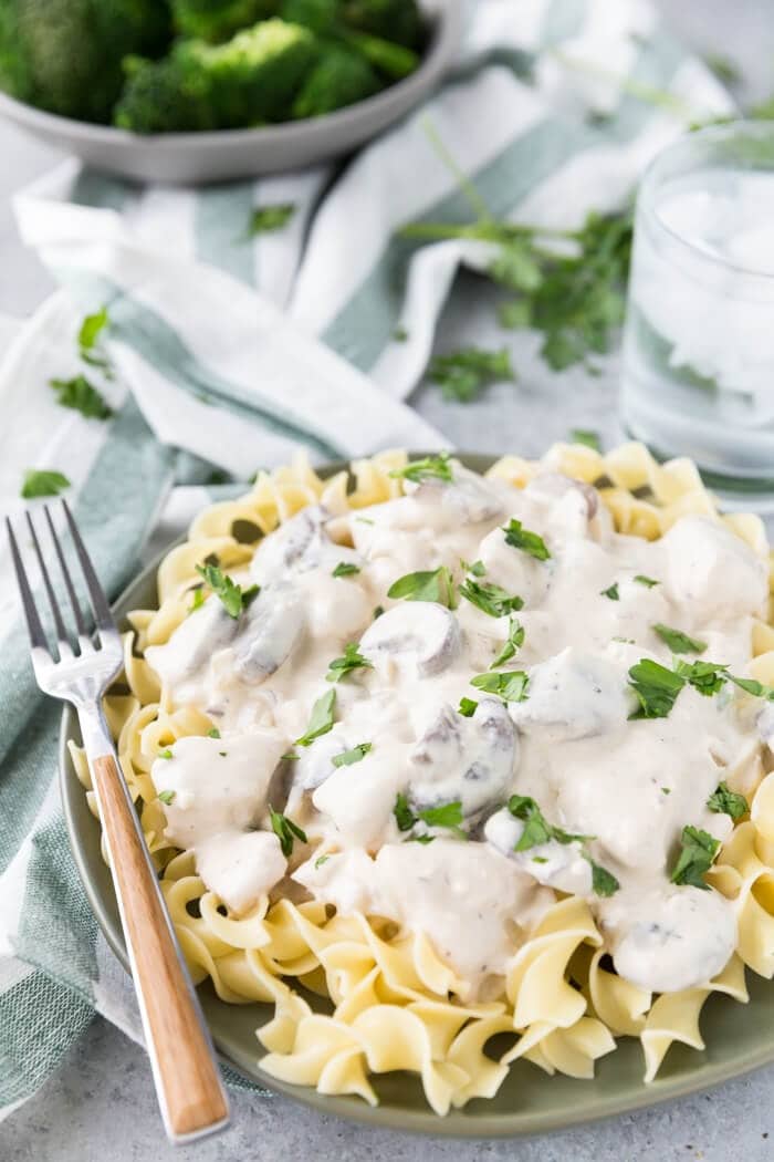 Chicken Stroganoff over pasta with sliced mushrooms and chicken breast garnished with parsley