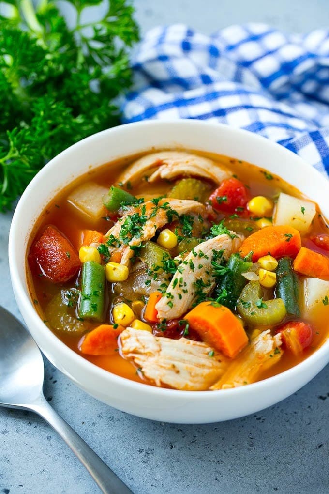 Bowl of chicken vegetable soup garnished with chopped cilantro leaves. 