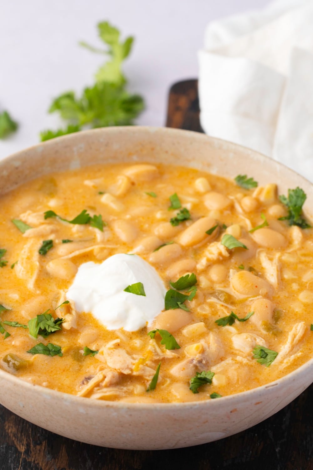 White chicken chili served on a bowl with cream and chopped parsley on top. 