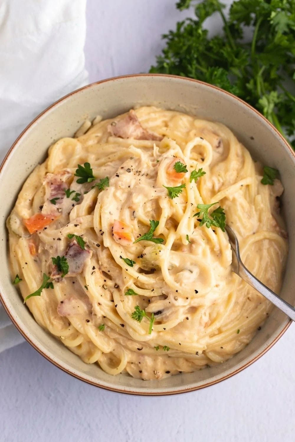 Fork dipped in a bowl of Crack Chicken Noodle Soup garnished with parsley