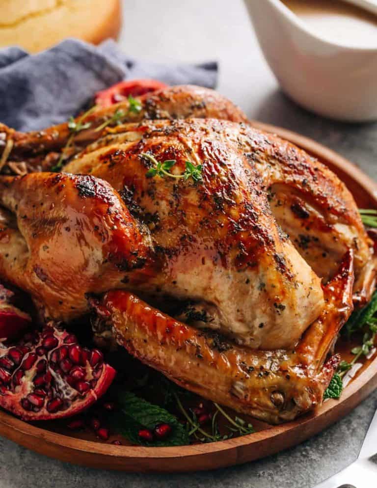 Close up view crispy skin Slow Cooker Turkey with herbs and pomegranate on a wooden plate