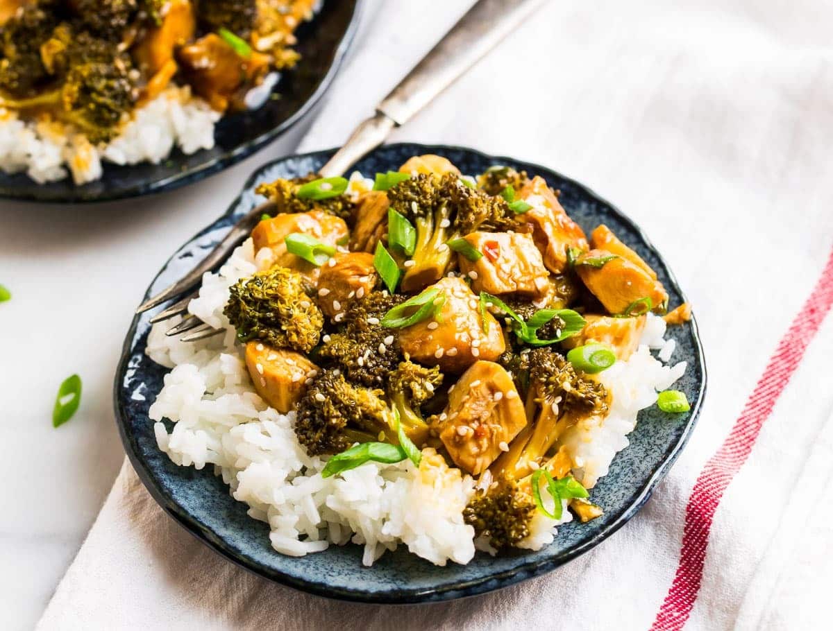 Plate of rice topped with Crockpot Chicken and Broccoli garnished with chopped spring onions and sesame seeds