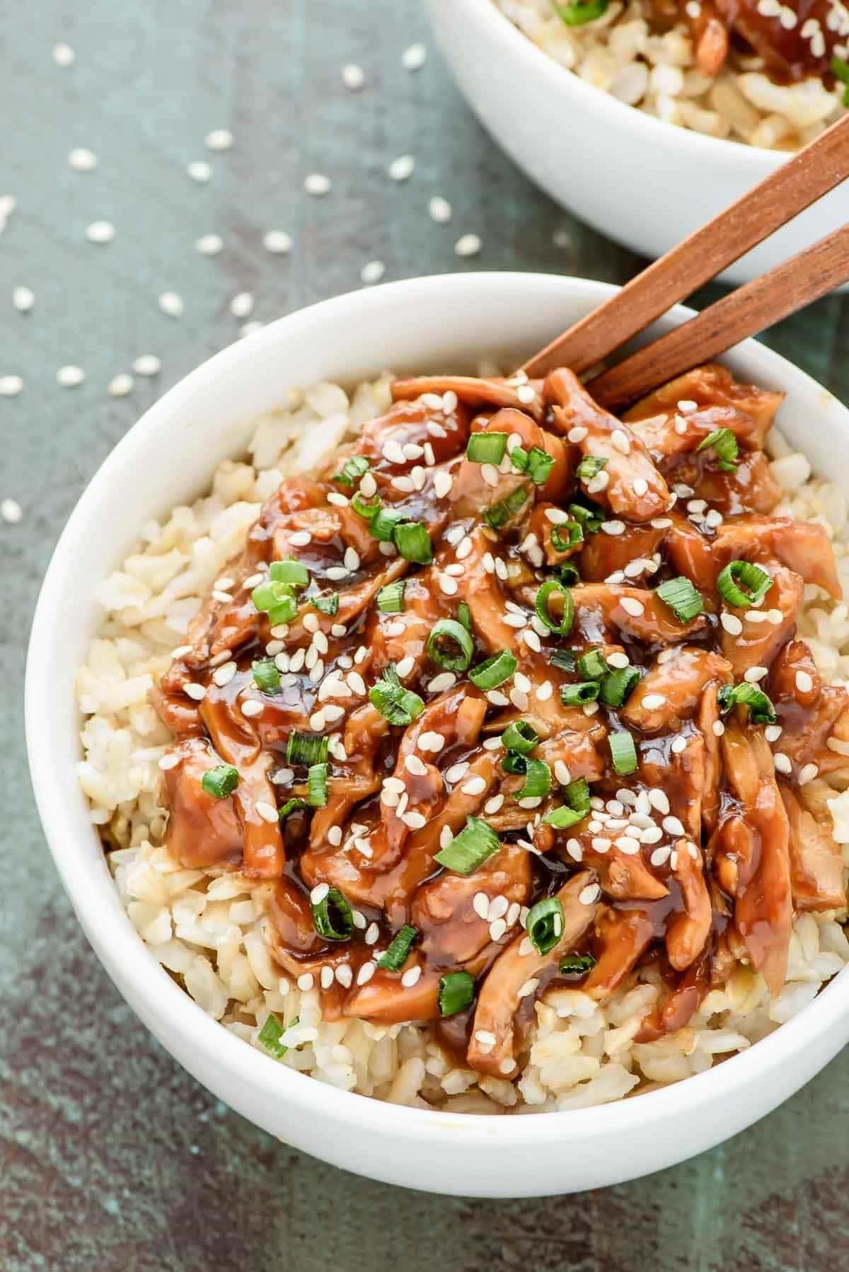 Bowl of homemade Crockpot Teriyaki Chicken garnished with chopped green onions and sesame seeds