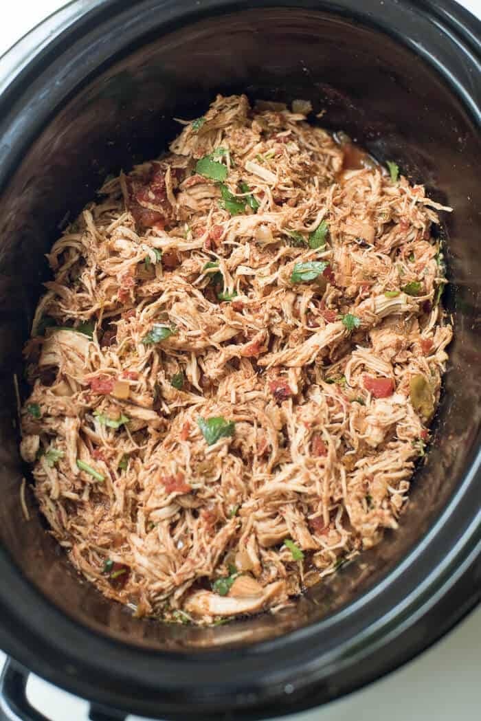 Easy Slow Cooker Chicken Enchiladas with cilantro, thinly sliced, green onions, diced tomato, chopped avocado, sliced black olives