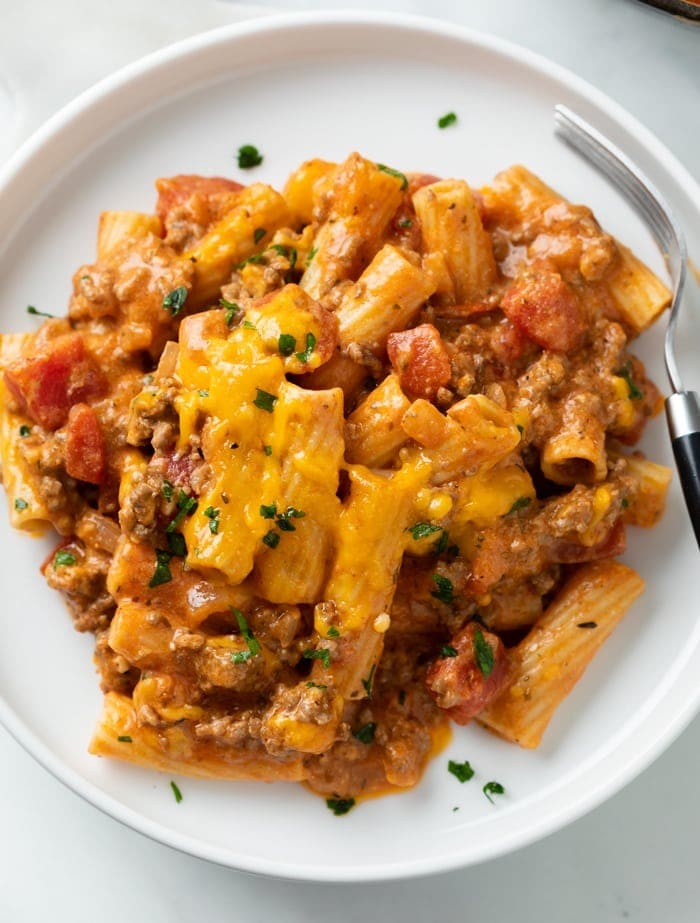 Serving of cheesy ground beef casserole on a white plate. 