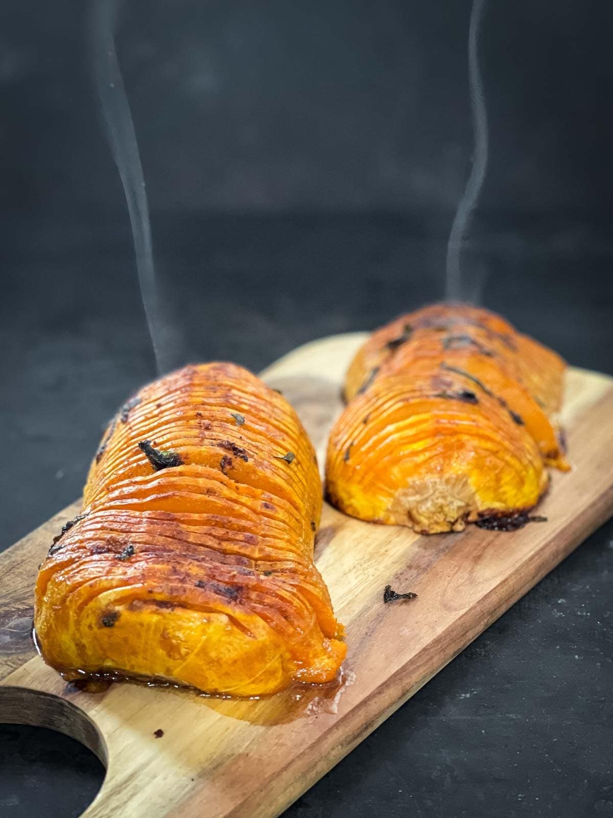 Sliced hasselback butternut squash in garlic butter on a cutting board. 