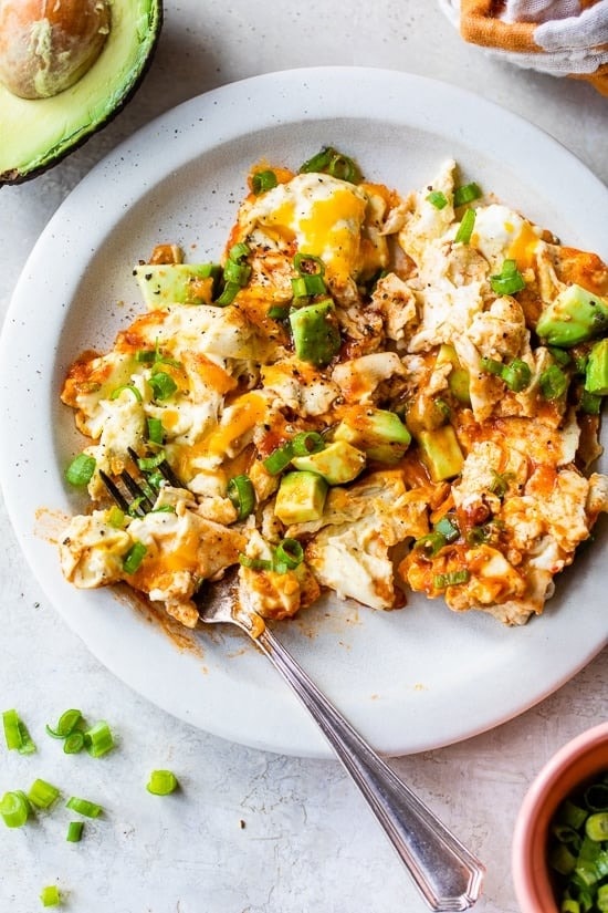 Homemade High-Protein Enchilada Scrambled Eggs served on a plate with fresh avocado