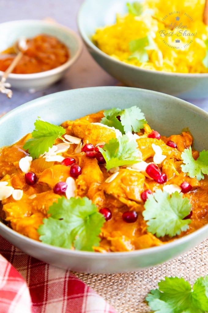 Bowl with leftover chicken curry garnished with pomegranate seeds and fresh cilantro leaves. 