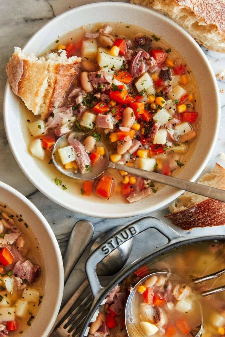 Leftover hambone soup made with white beans, potatoes, corn, onion, and carrots in a pot and served on bowls.