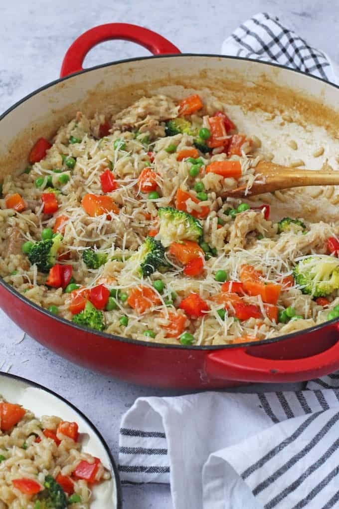 Leftover roast chicken risotto in a pan mixed with a wooden spoon. 