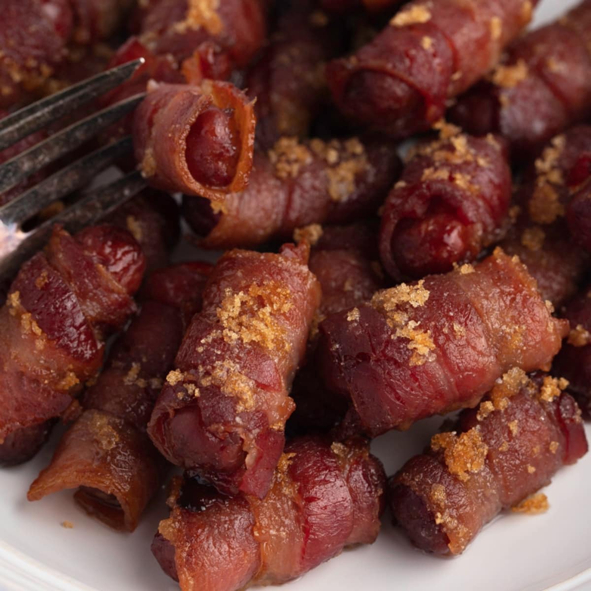 Closeup of bacon wrapped little smokies in a plate. 