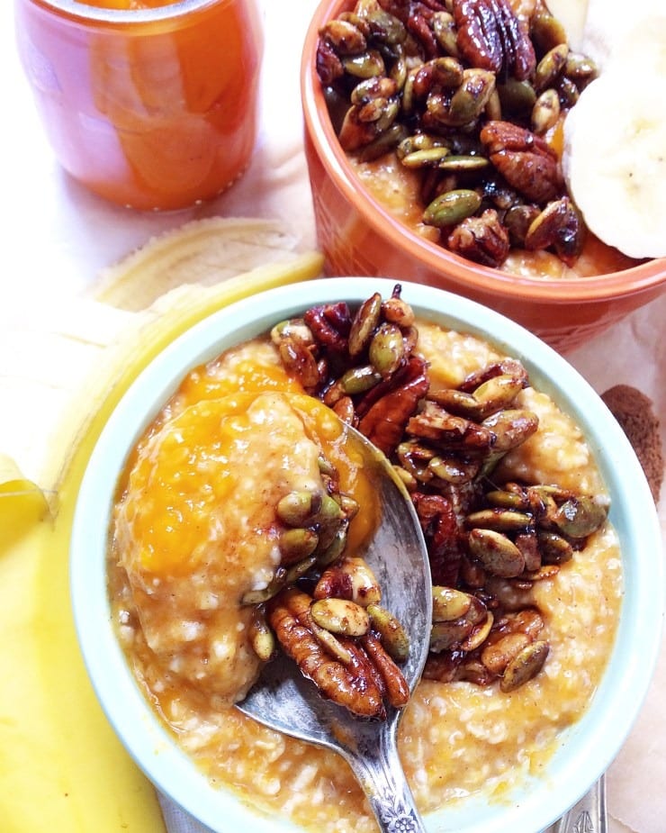 Pumpkin pie oatmeal with maple cinnamon pecans on a white bowl with spoon. 